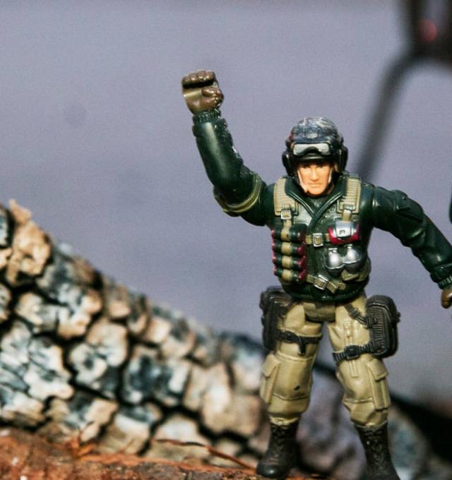 twee speelgoedsoldaatjes op een stuk brandhout