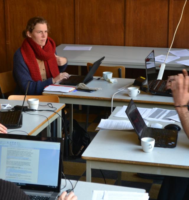 vijf mensen rond verschillende tafels, achter een computer discussiëren over dingen die ze gevonden hebben.